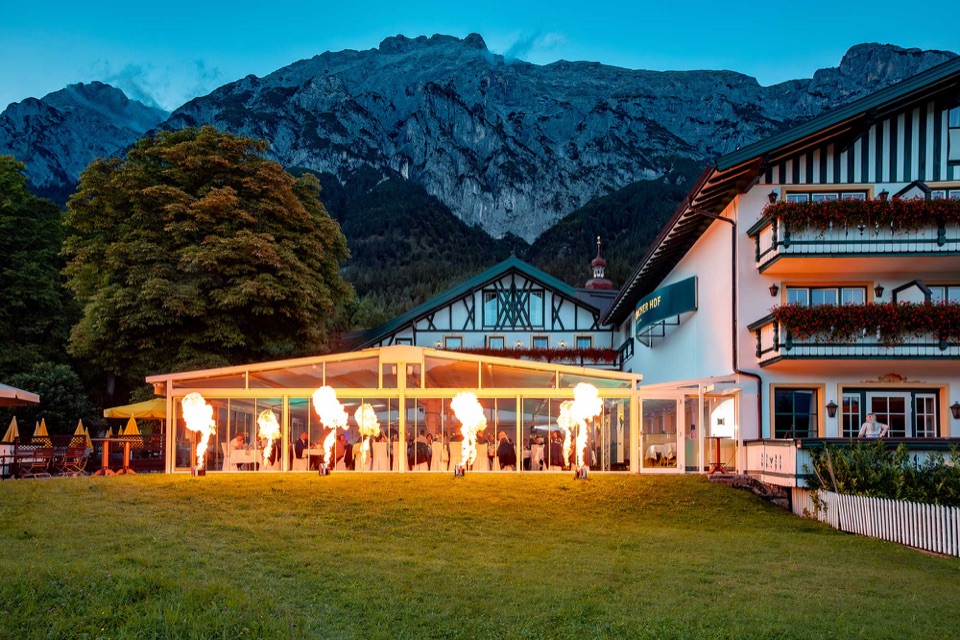 Beleuchteter Wintergarten des Speckbacherhofs vor der Tiroler Bergkulisse